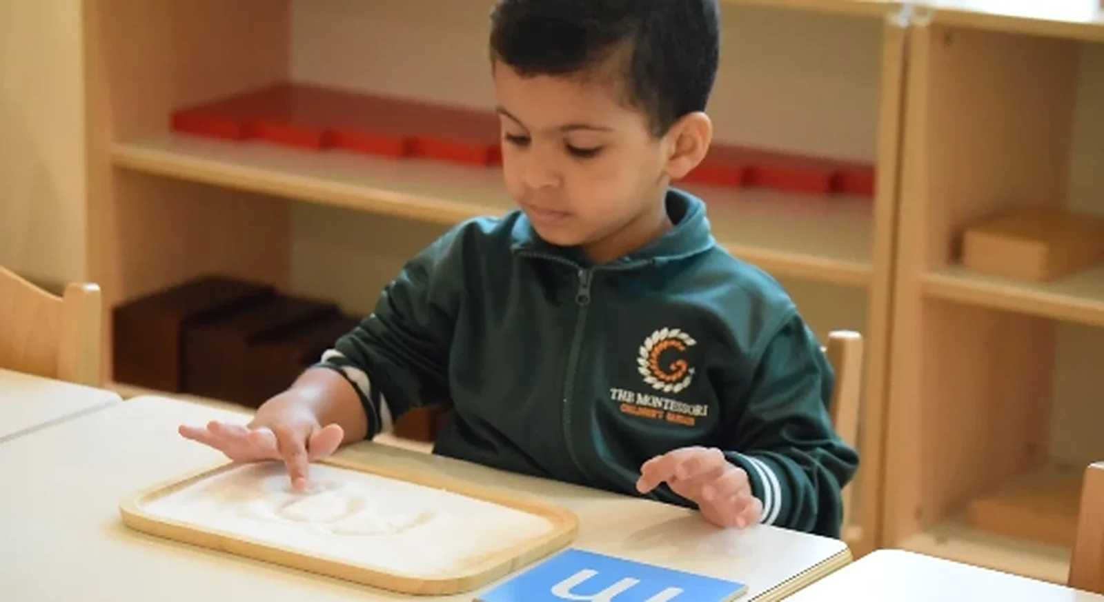 A TMCG child developing early language skills in the prepared Montessori classroom