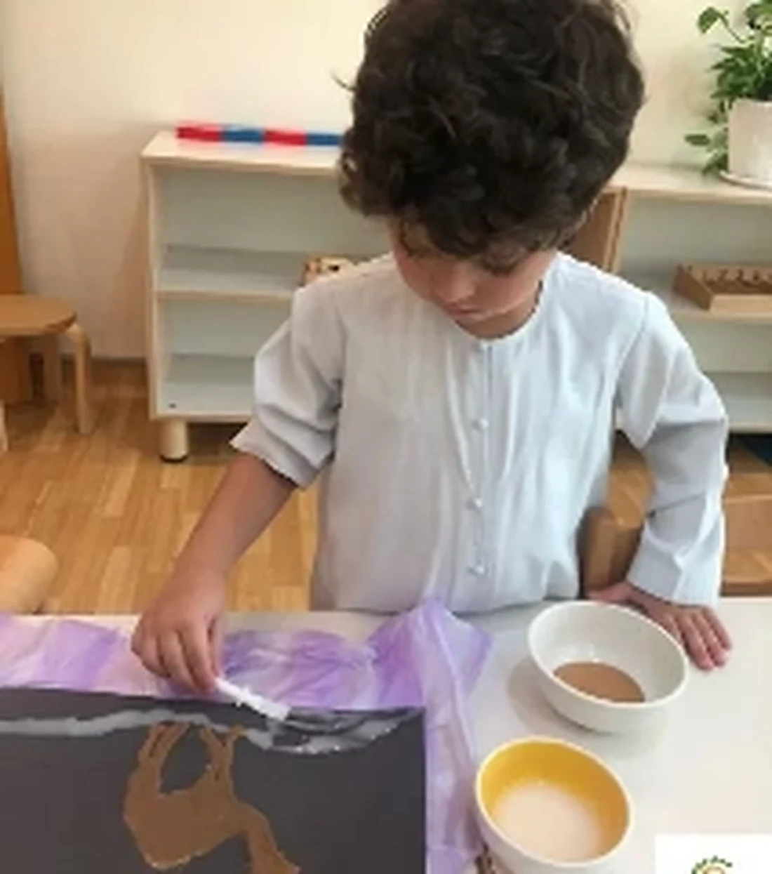A TMCG child practising a careful pouring activity in the classroom